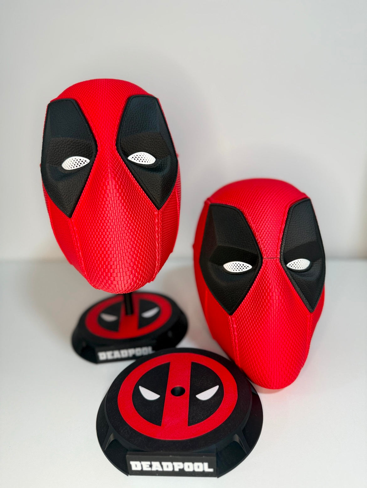 Red and black 3D printed Deadpool helmets with display stands